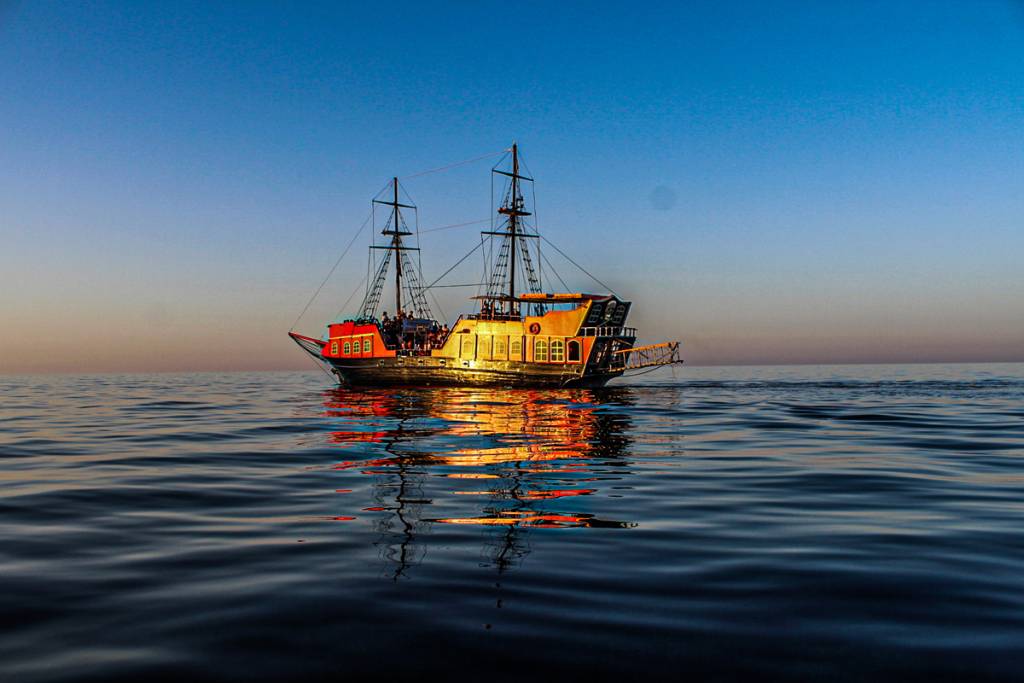 A beautiful sunset over Crete with a pirate ship in view - Experience a peaceful and private boat trip away from the crowds.